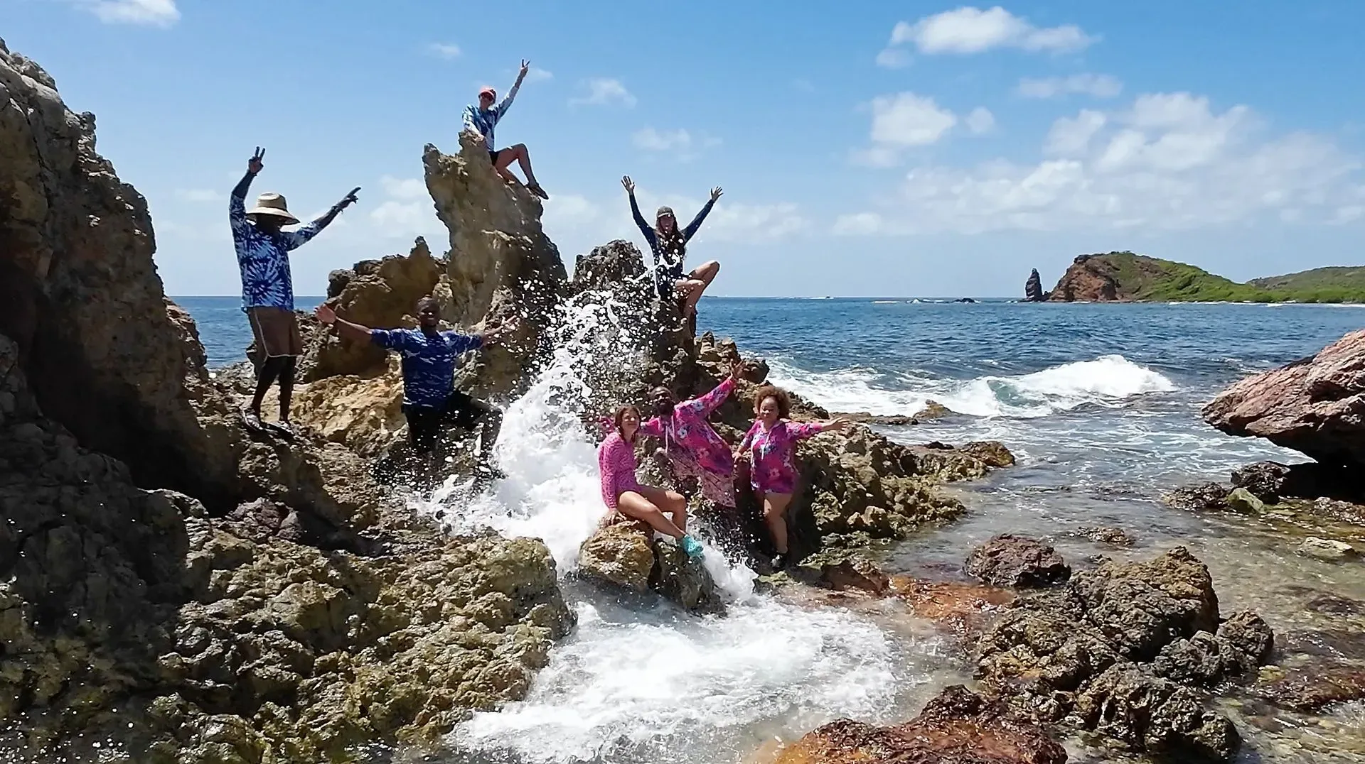 A group of people standing on rocks near the ocean