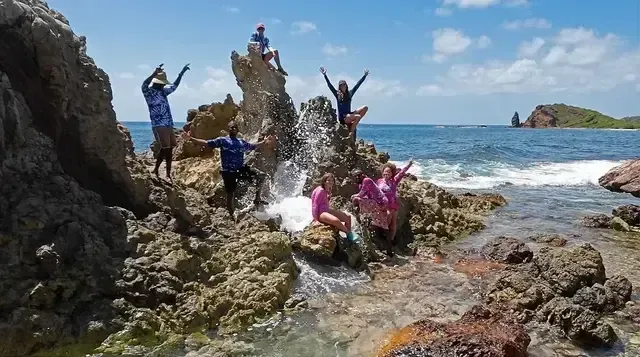 A group of people standing on rocks near the ocean