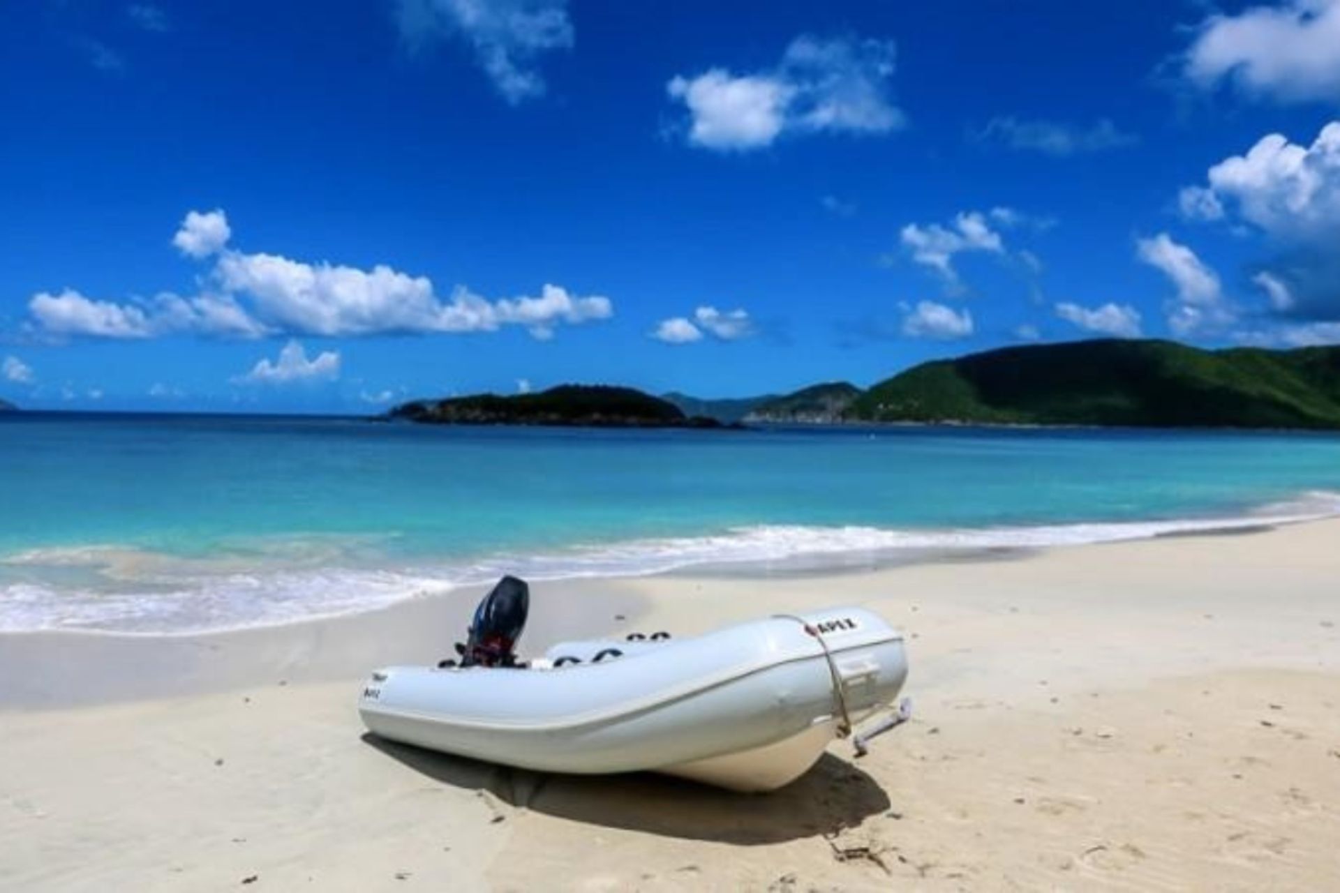 A boat with a motor is sitting on the beach.