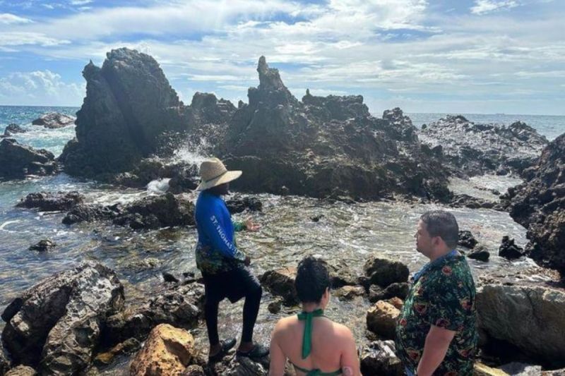 A group of people are standing on rocks near the ocean.