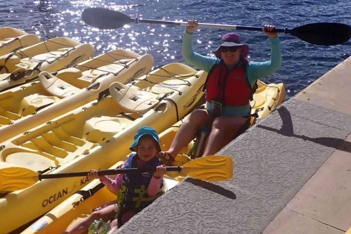 A woman and child are in a row of yellow ocean kayaks