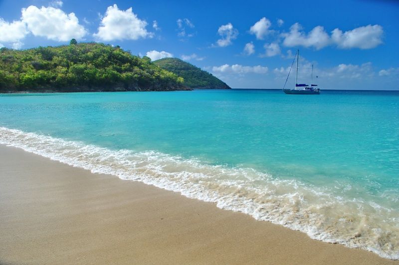 A boat is floating on the water near a sandy beach.