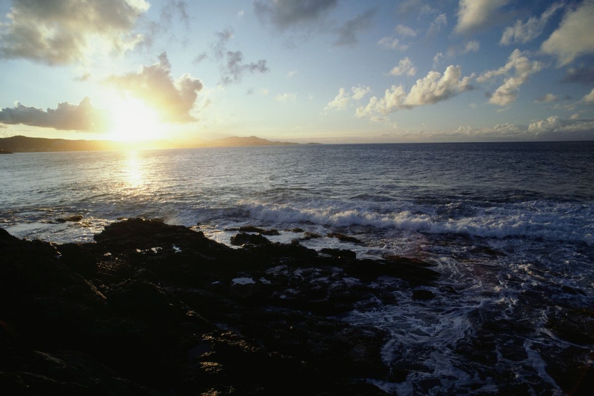 A sunset over a body of water with rocks in the foreground