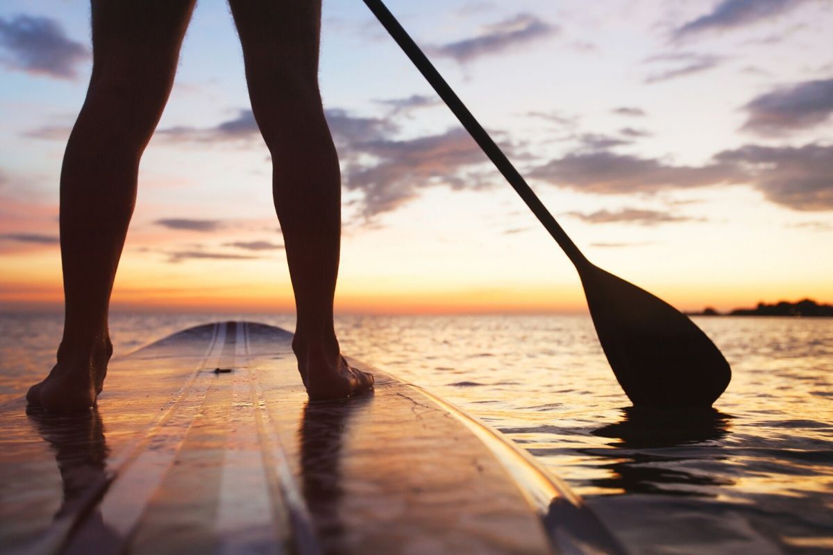 A person is standing on a paddle board in the ocean