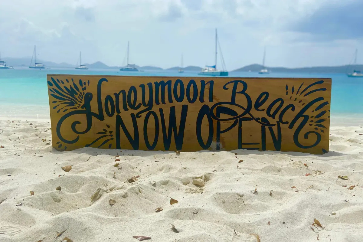 A sign on a beach that says honeymoon beach now open