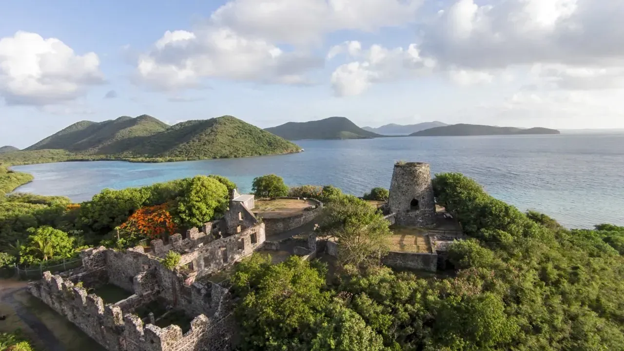 An aerial view of a castle on a small island in the middle of the ocean.