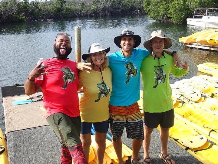 A group of people posing for a picture with kayaks in the background