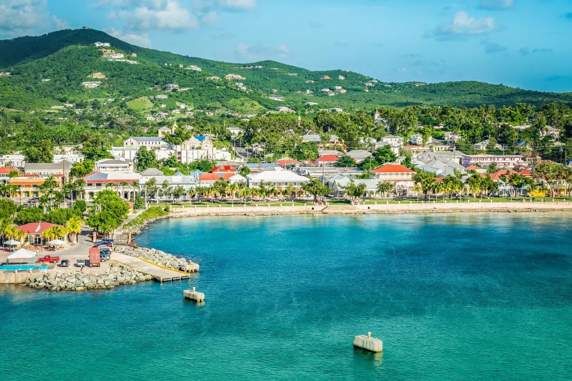An aerial view of a small town on a tropical island with a boat in the water.