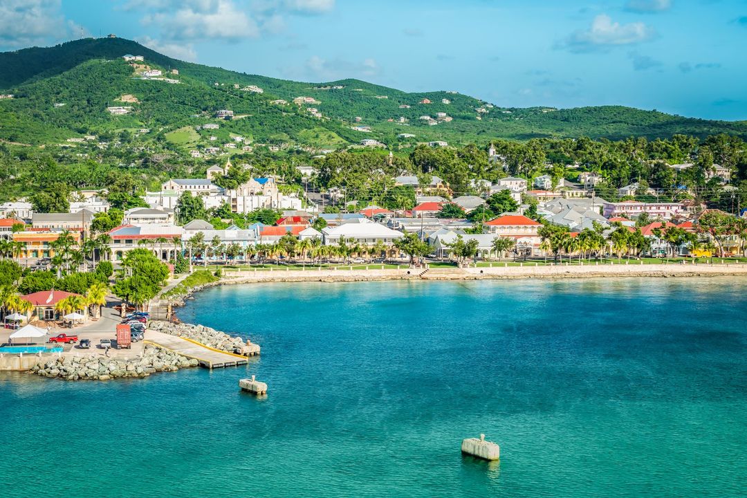 An aerial view of a small town on a tropical island with a boat in the water.