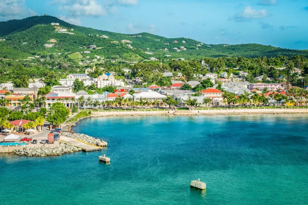 An aerial view of a small town on a tropical island with a boat in the water.