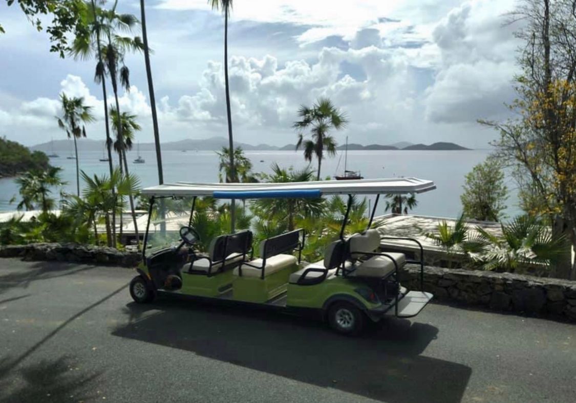 A green golf cart is parked on the side of a road.