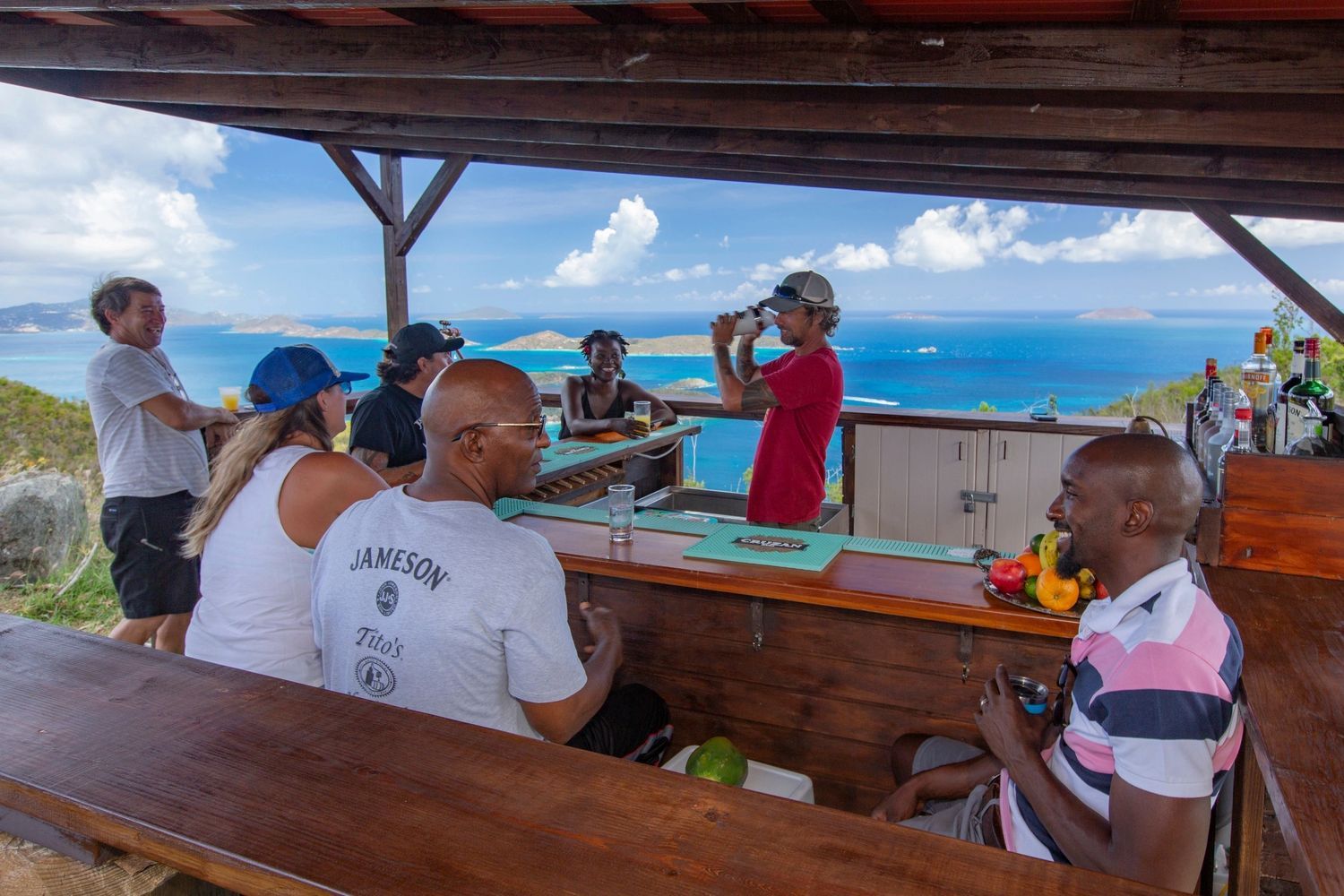 A group of people are sitting at a bar overlooking the ocean.