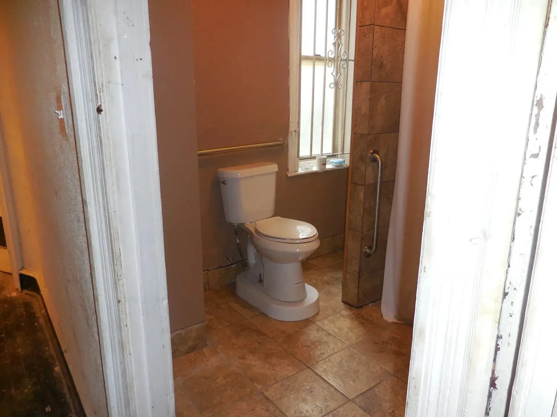A toilet in a bathroom next to a window