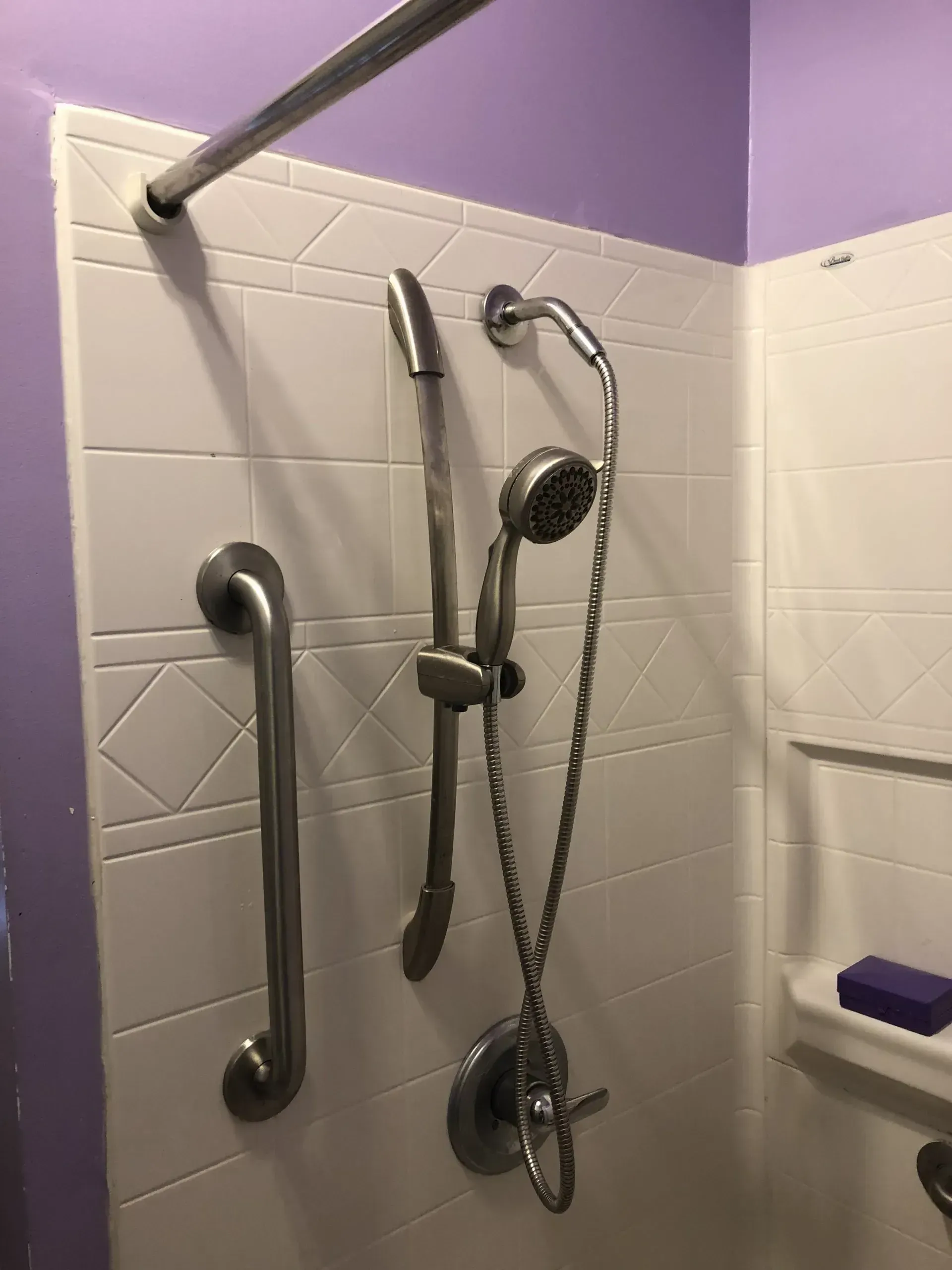 A shower with a hand rail and a shower head.