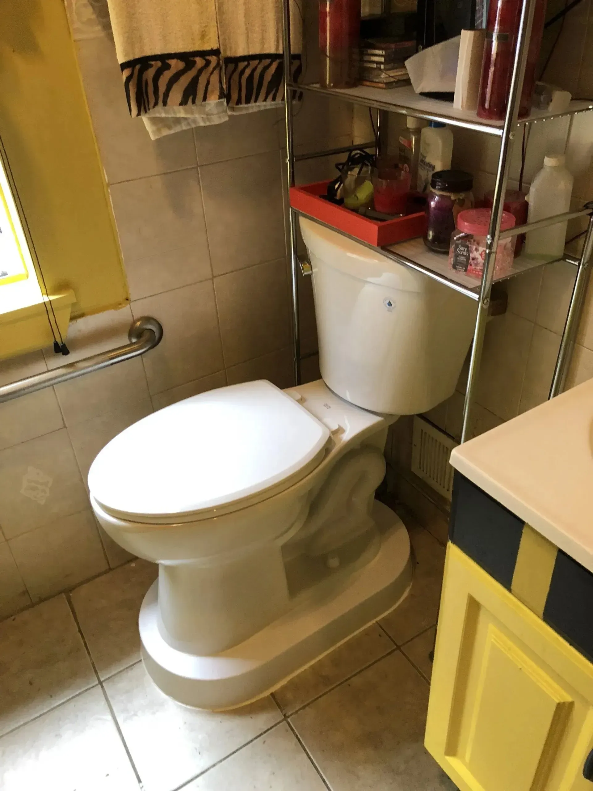 A toilet is sitting in a bathroom next to a window.