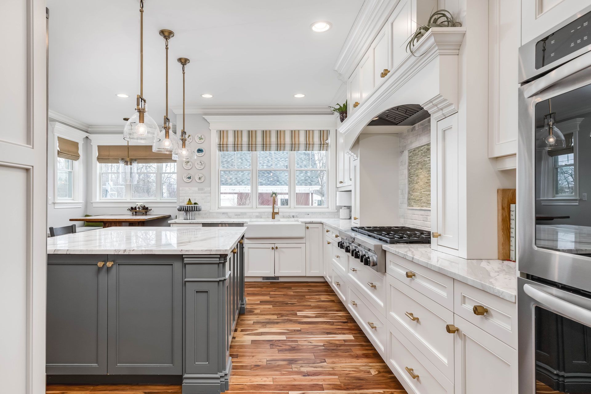 A kitchen with white cabinets , stainless steel appliances , wooden floors and a large island.