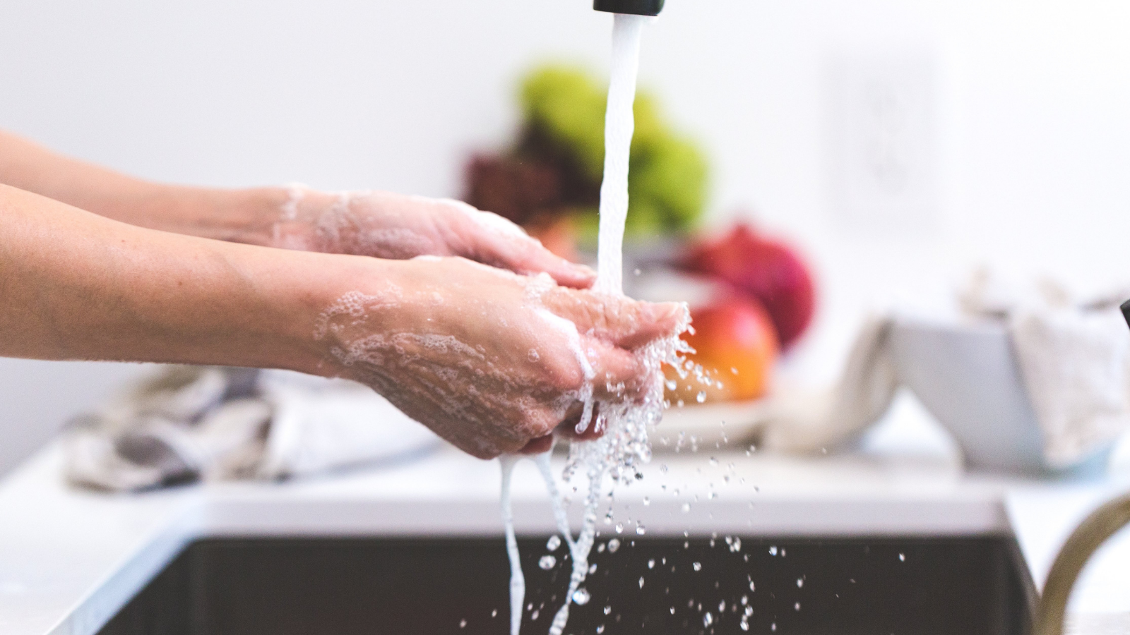 A person is washing their hands in a kitchen sink.