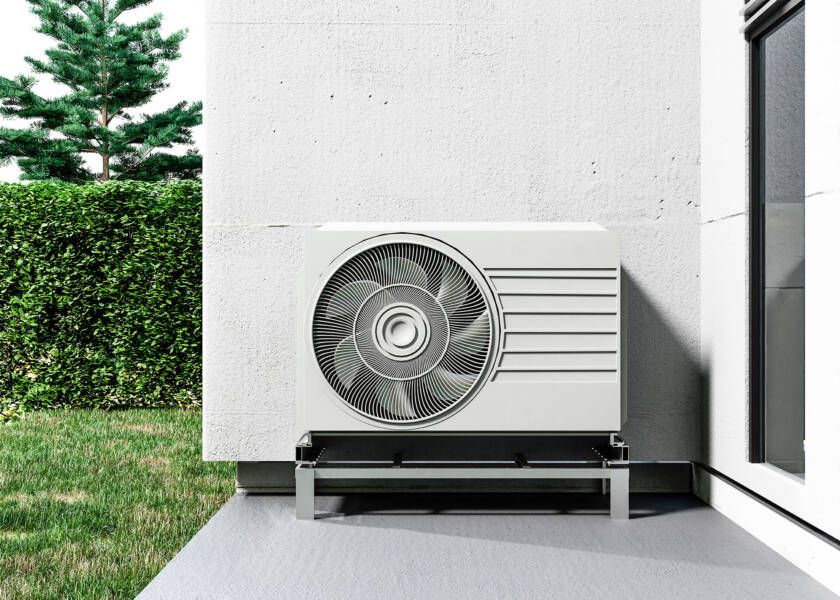 A white air conditioner is sitting on the side of a building.