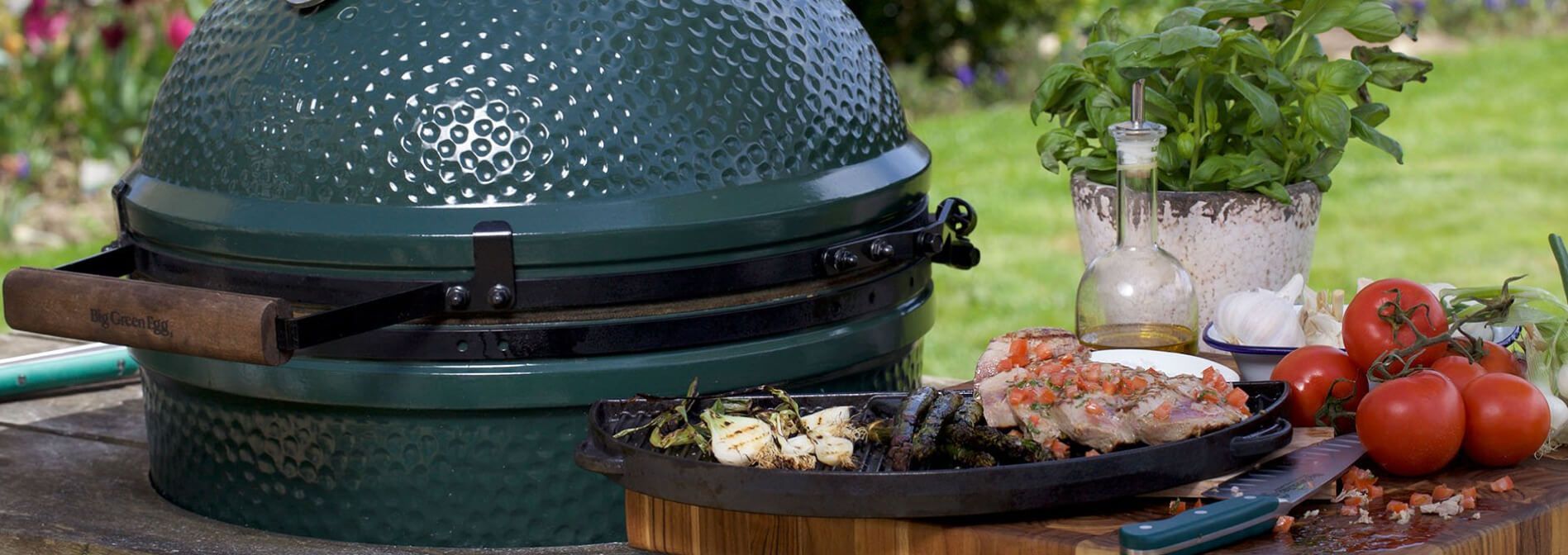 A large green egg grill is sitting on top of a wooden table.