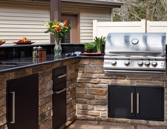 A large outdoor kitchen with a sink , refrigerator , and umbrellas.