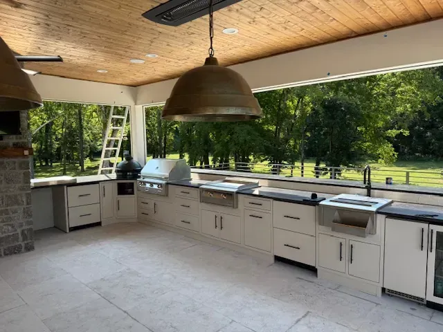 A large outdoor kitchen with a sink , refrigerator , and umbrellas.