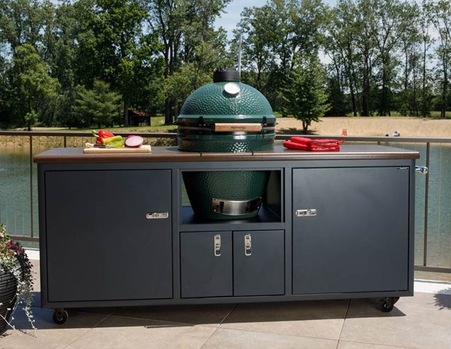 A large green grill is sitting on top of a black cabinet