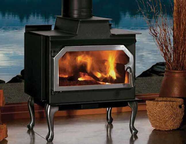 A wood stove is sitting in a room with a view of a lake in the background.