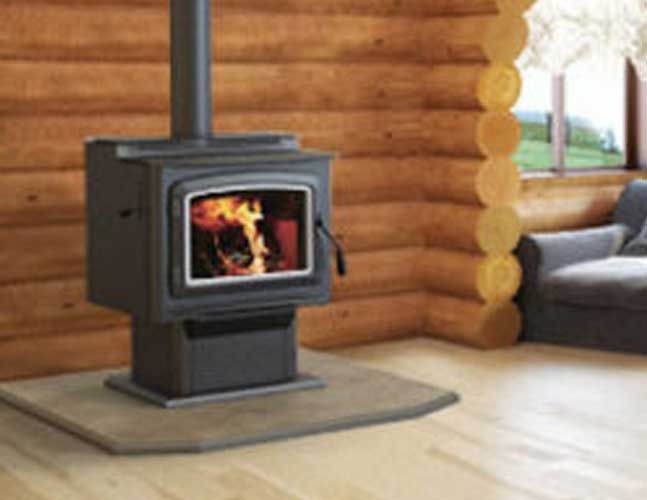 A wood stove is sitting in a living room next to a window.