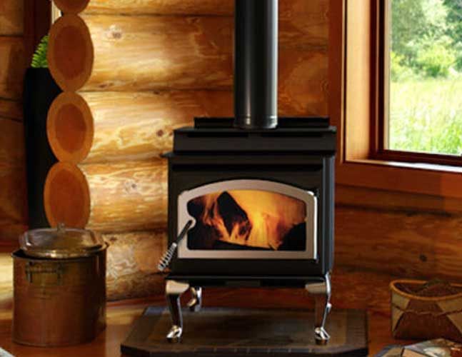 A wood stove is sitting in a log cabin next to a window.