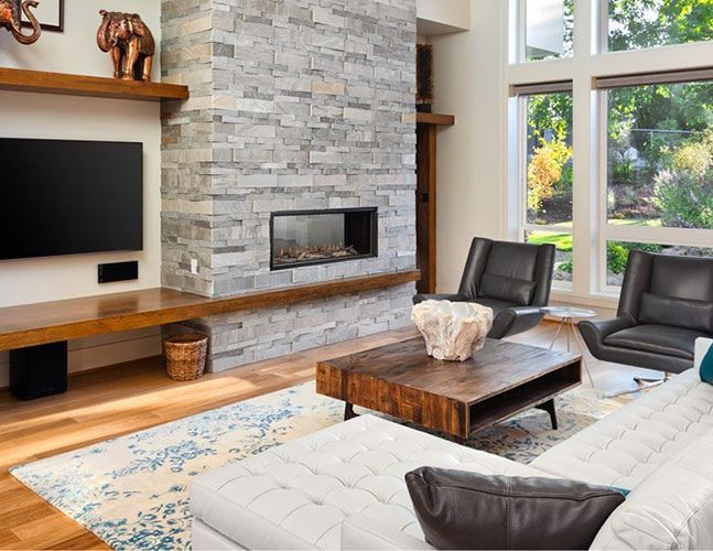 A living room with a fireplace , couch , chairs , coffee table and television.
