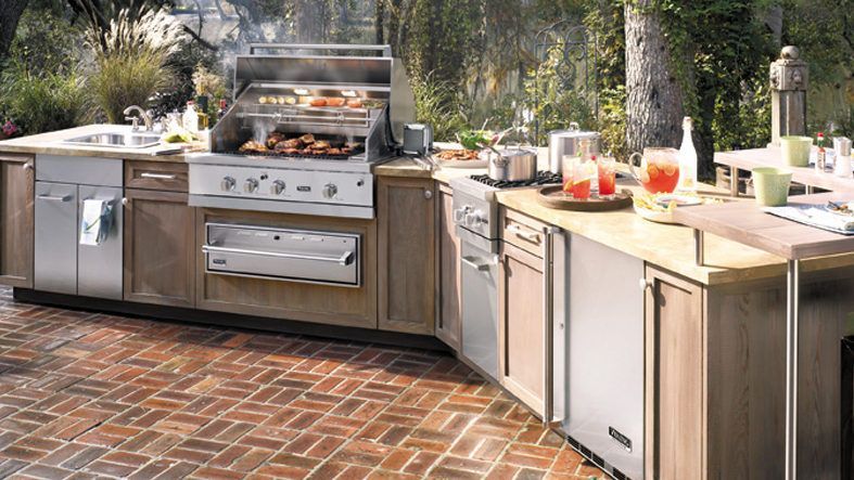An outdoor kitchen with a grill , sink , and dishwasher.