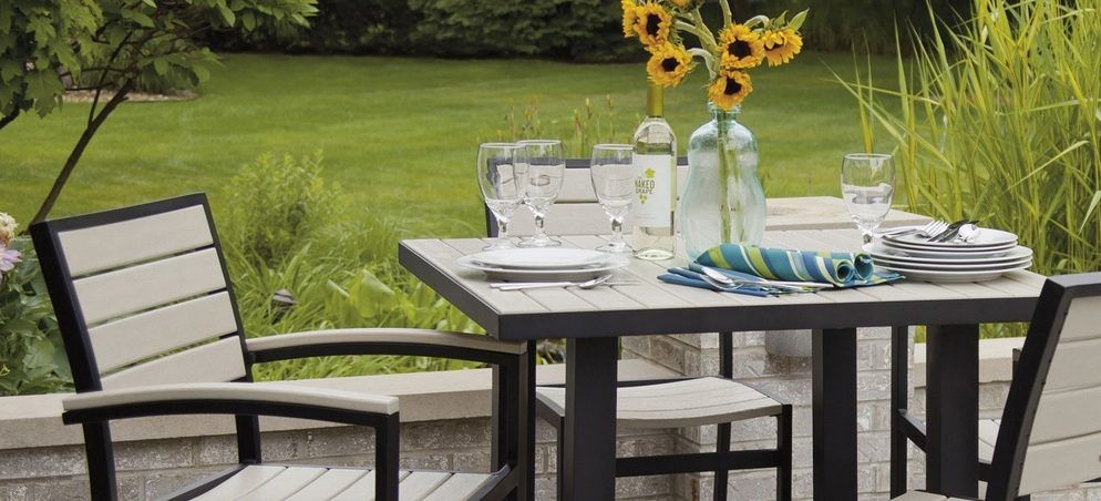 A table and chairs are sitting on a patio in front of a lush green field.