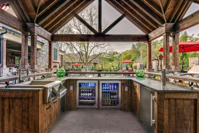 A large outdoor kitchen with a sink , refrigerator , and umbrellas.