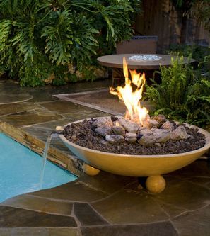 A fire pit is sitting next to a swimming pool.