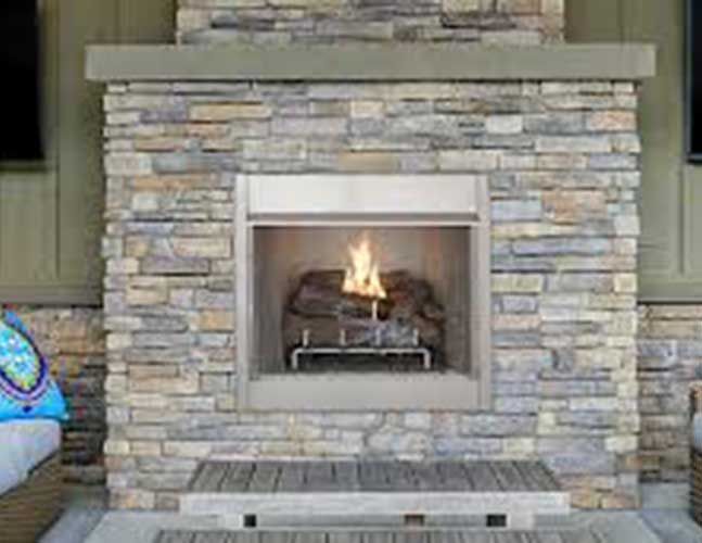 There is a fireplace in the middle of a stone wall.