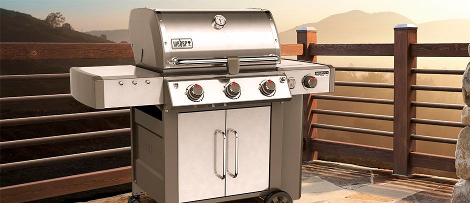 A stainless steel grill is sitting on a patio next to a railing.