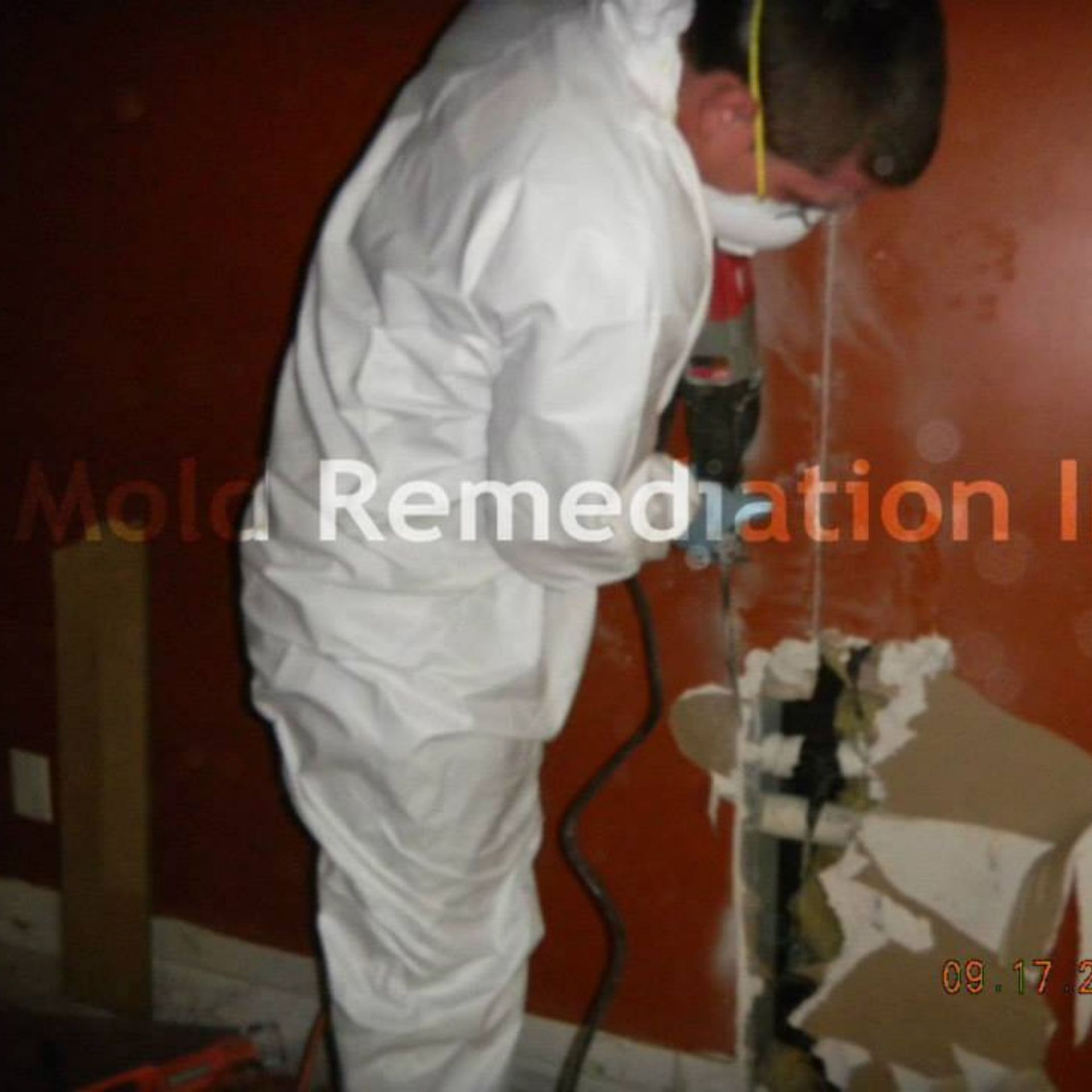 Mold Remediation Inc -A man in a white suit is working on a wall with mold remediation written on the bottom