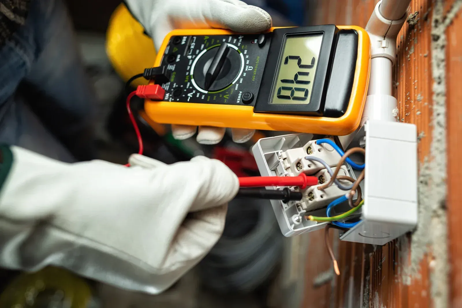 An electrician is using a multimeter to test an electrical outlet.
