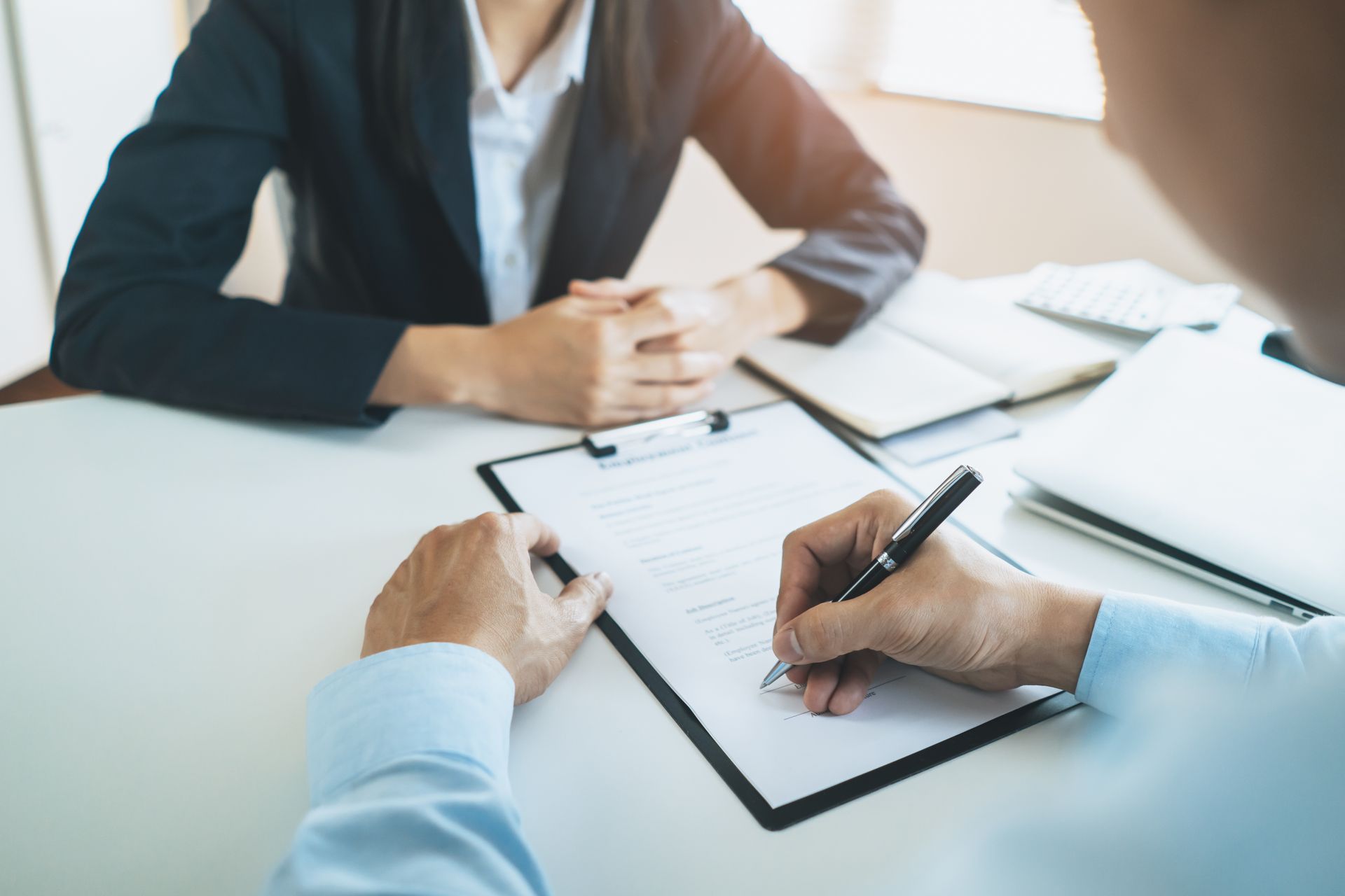 Person signing signature into employment contract. Person signing signature into employment contract.