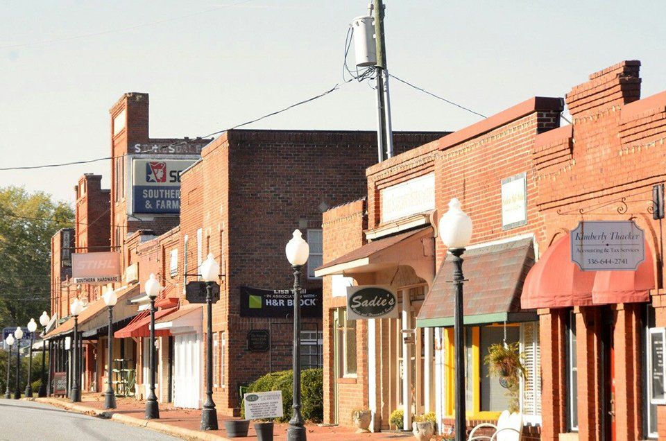 Row of brick buildings with awnings and streetlights along a street in a small town.