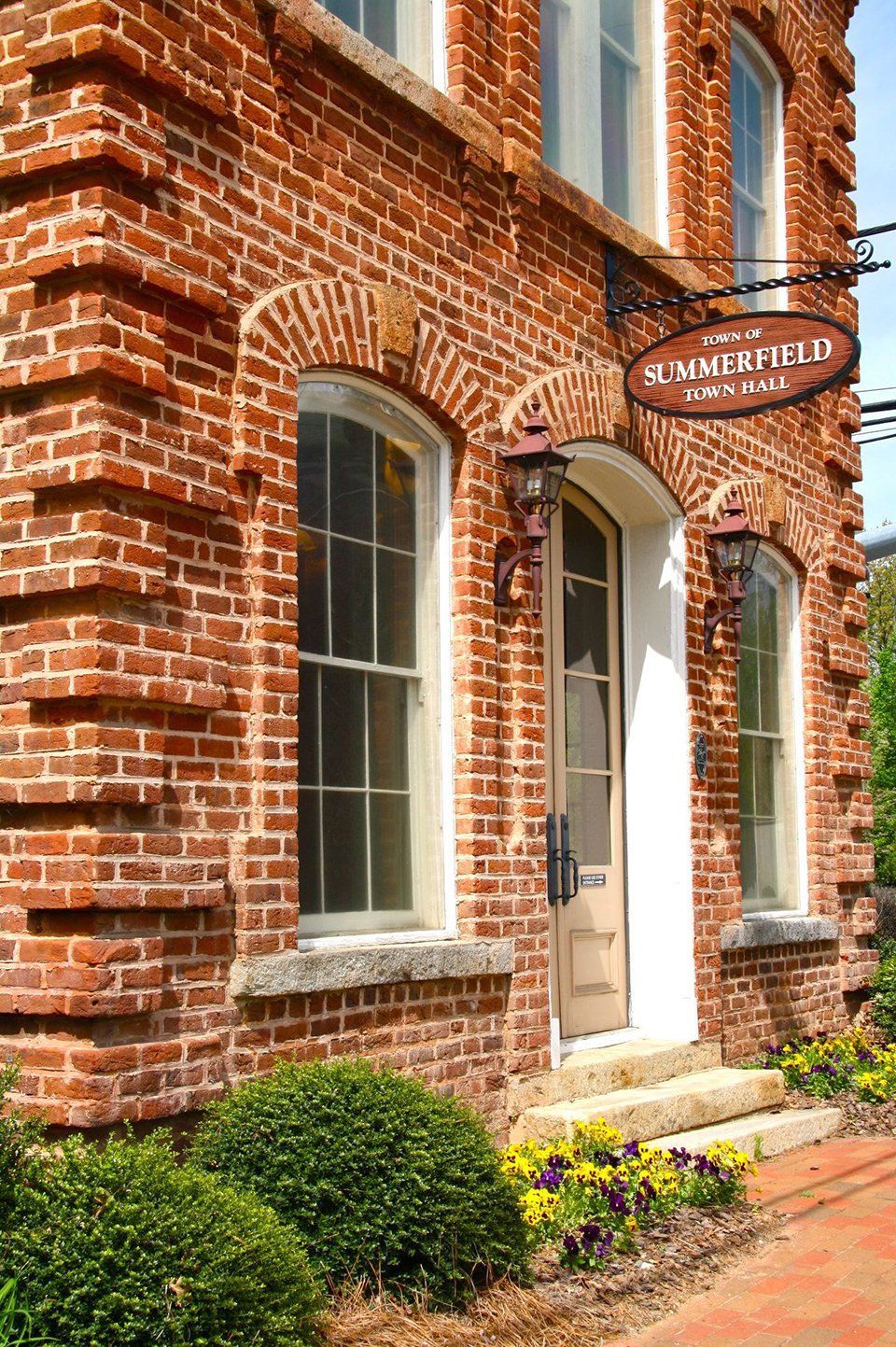 Brick building with arched windows, door, and a sign that says 