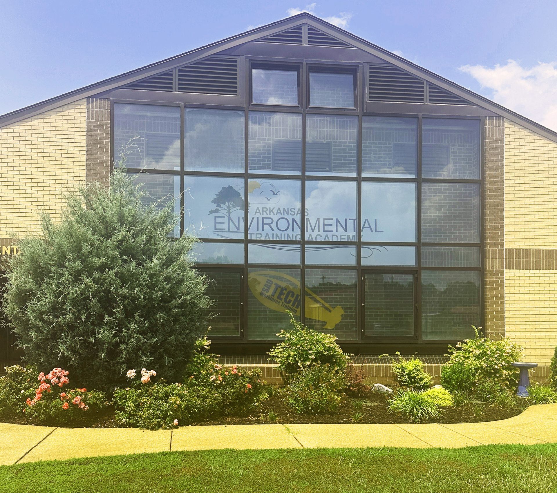 Brick sign for Arkansas Environmental quality office with shrubs in front and parked vehicles behind