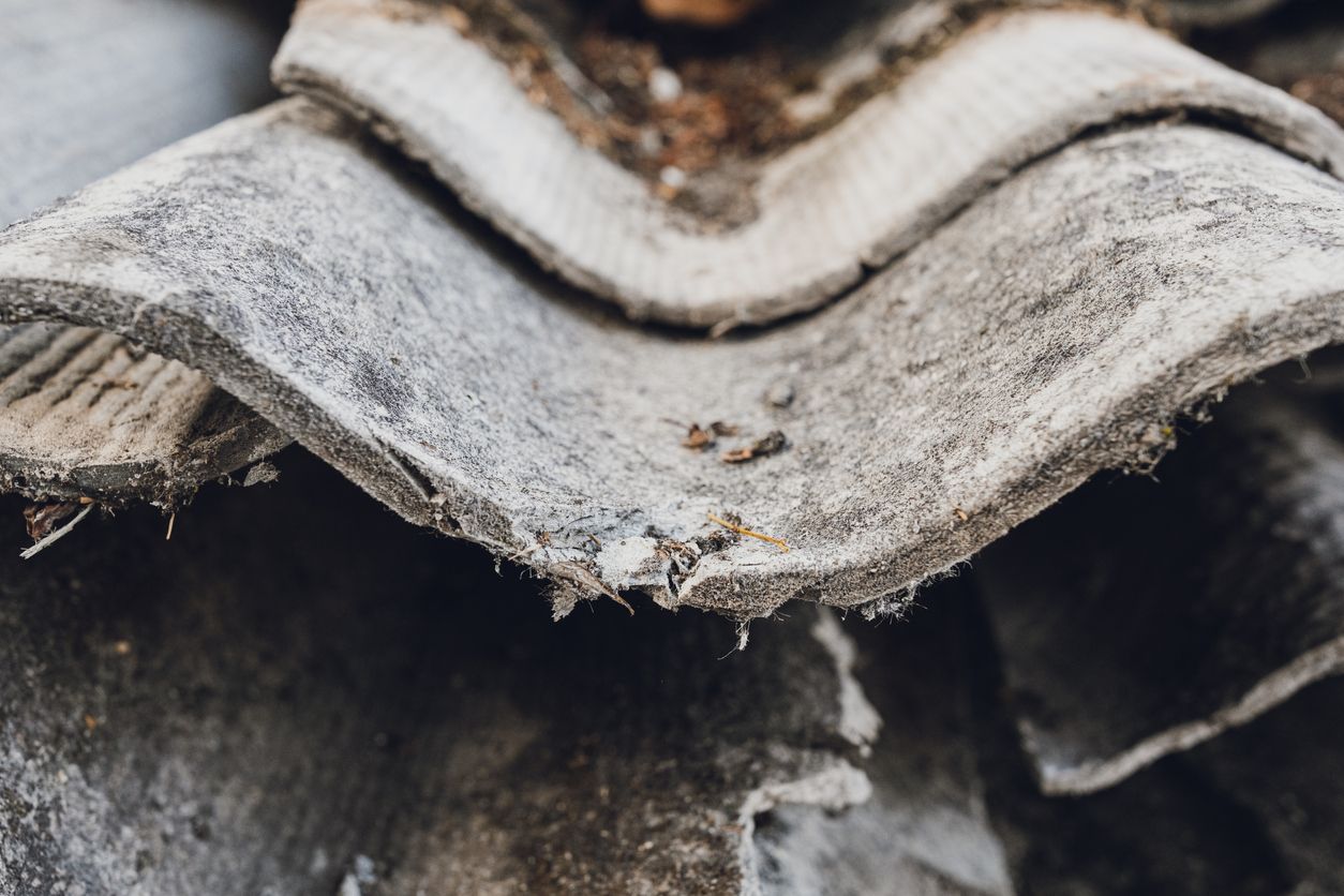 Close-up of weathered gray corrugated roofing with chipped edges and rust spots