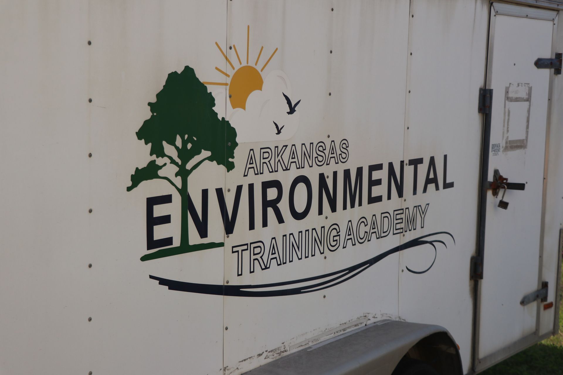 White trailer with Arkansas Environmental Training Academy logo and tree-sun graphic on the side