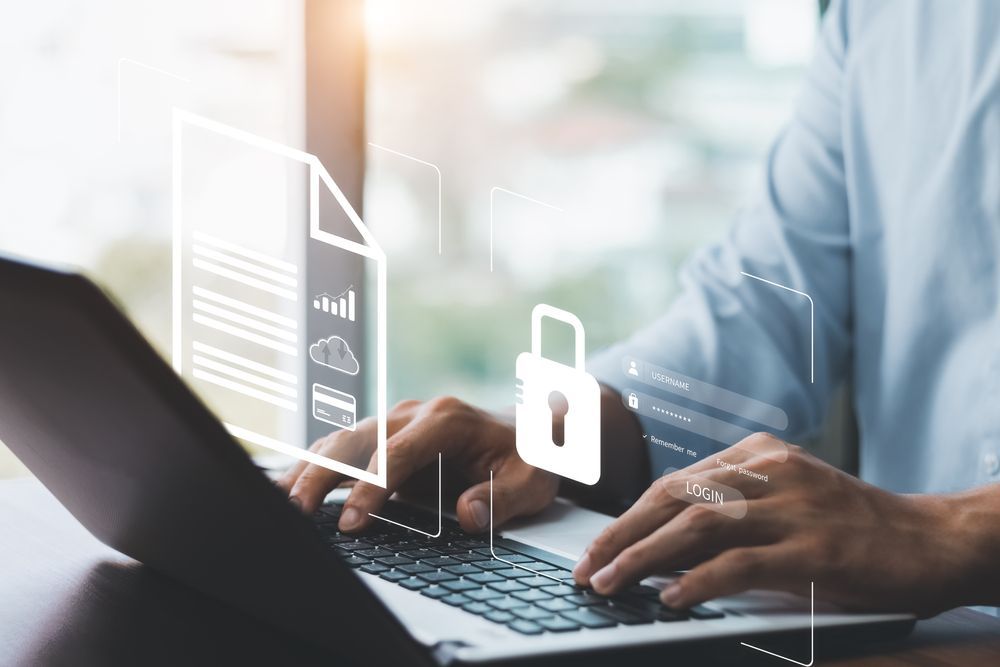 Hands typing on a laptop with a white security lock icon overlay in a bright office setting