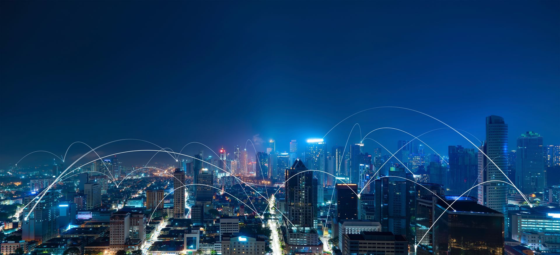 An aerial view of a city at night with a lot of lights on the buildings.