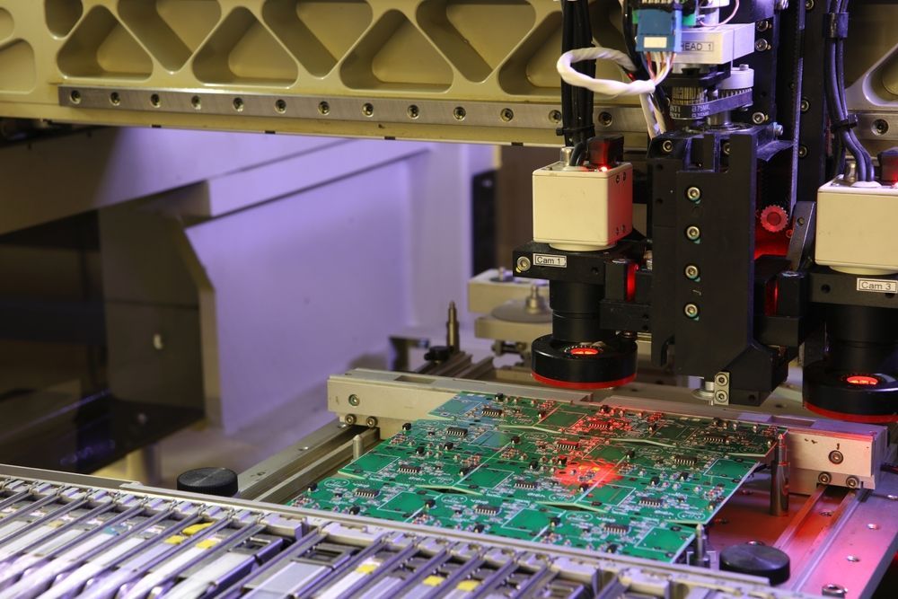 Automated machine inspecting a green circuit board on a factory conveyor belt