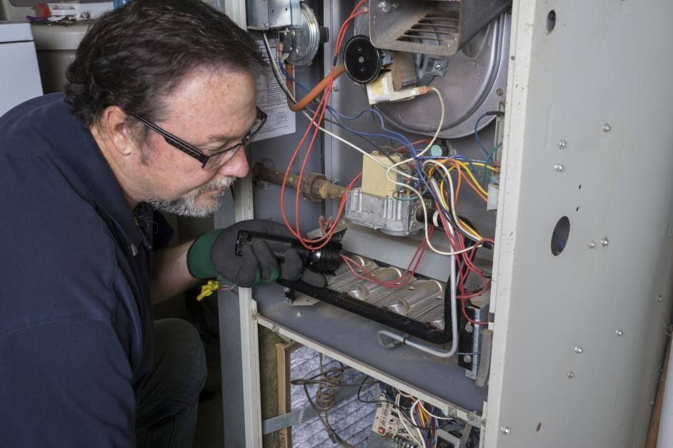 A man is working on a heating system with a wrench.