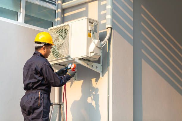 A man is working on an air conditioner on the side of a building.