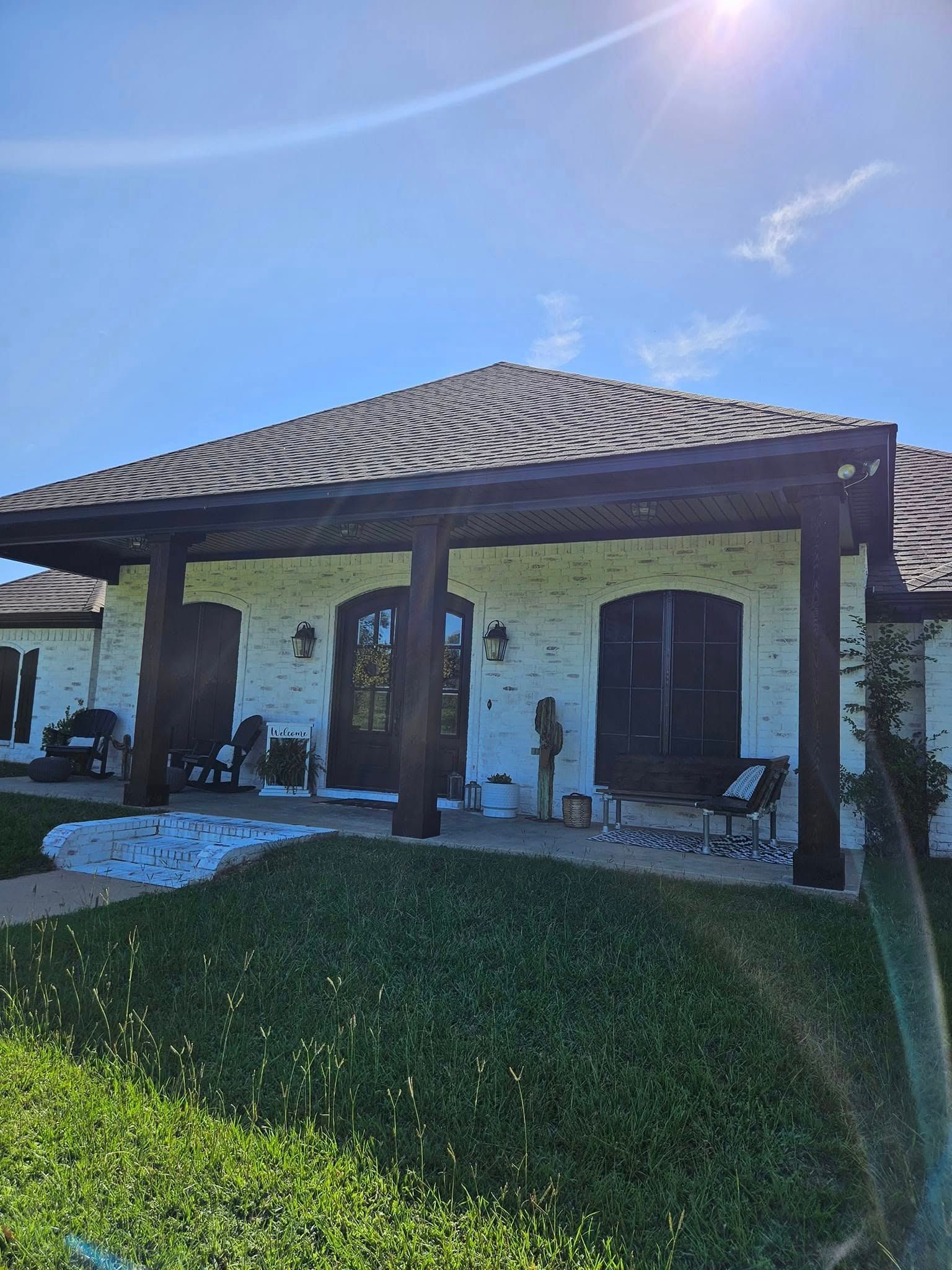 White brick house with dark wooden beams, blue sky and bright sun.